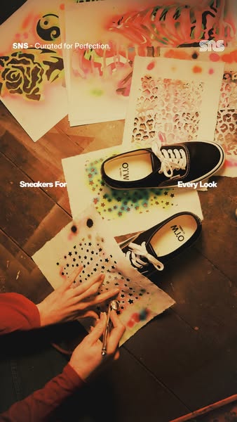 This image ad for SNS highlights a pair of black sneakers. The ad features an artistic theme with hands using an airbrus