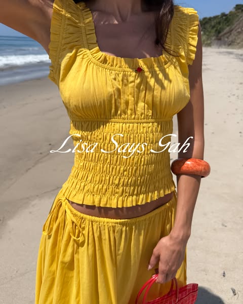 This image ad showcases a yellow Lisa Says Gah outfit on a model, set on a beach.