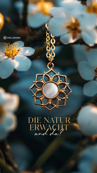 A close-up shot of a golden pendant necklace hanging in front of white spring blossoms. The ad targets an audience looki