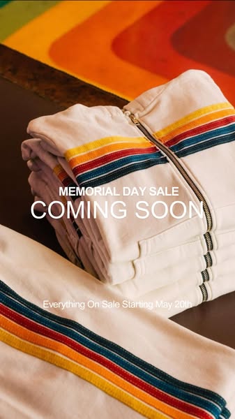 This ad announces a Memorial Day sale that is coming soon. It features a stack of folded white hoodies with colorful str