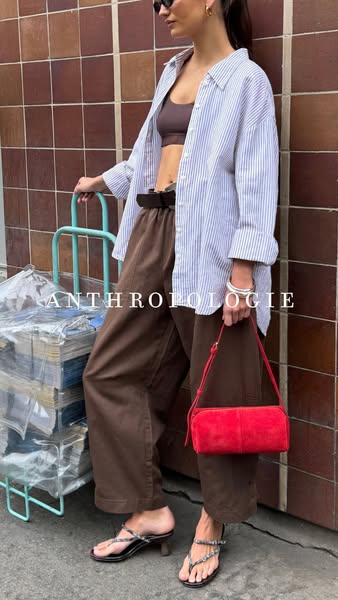A lifestyle ad for Anthropologie clothing. The ad features a young woman in brown trousers, a brown bra top, and a white