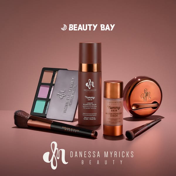 This ad showcases a variety of Danessa Myricks Beauty products, including a palette, brush, blurring balm, and water pow