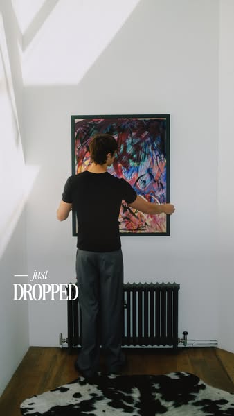 This image shows a man hanging art in a room, announcing the arrival of new artworks.