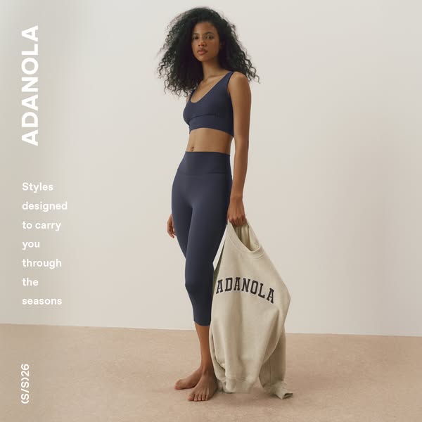 This image ad features a woman wearing a matching sports bra and capri legging set from Adanola. She is holding a sweats