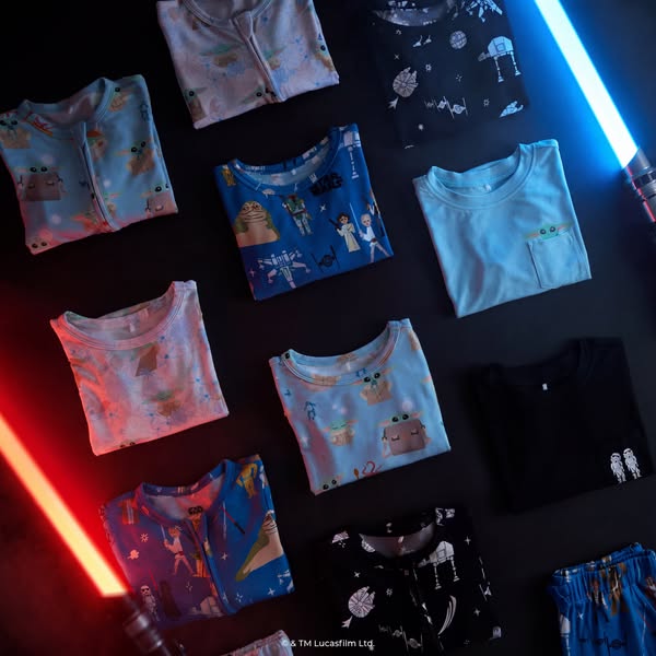 A product shot of Star Wars-themed baby and toddler pajamas are laid out in a grid pattern with Star Wars lightsabers vi