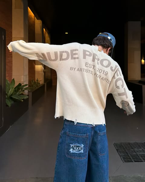 This image ad showcases a person wearing a light-colored sweater with the brand 'Nude Project' printed on the ba