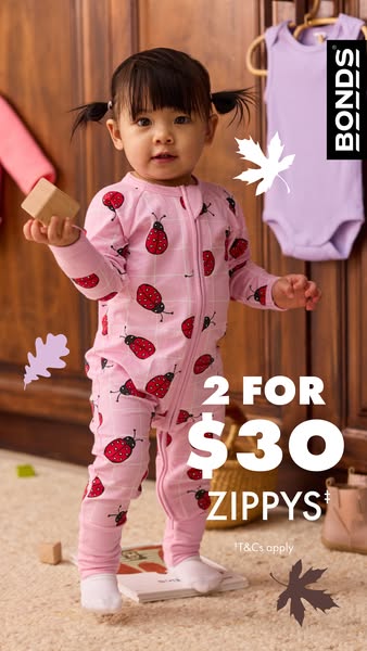 An image ad for Bonds baby zippys featuring a young girl in a ladybug-print onesie, set in a cozy, playful indoor enviro
