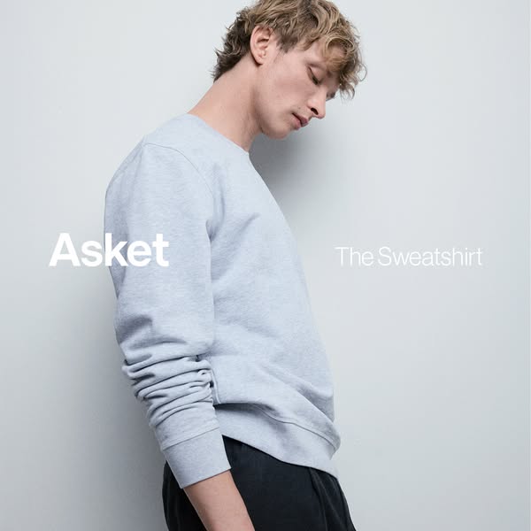 An ad for Asket's sweatshirt features a man wearing the heather gray sweatshirt. The brand name is in the lower left