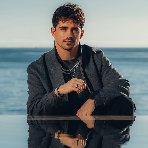 This ad features Charles Leclerc wearing various jewelry pieces in front of a waterfront background. The jewelry pieces 