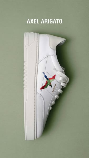 This ad showcases a white Axel Arigato sneaker with a colorful bird design on a solid green background.