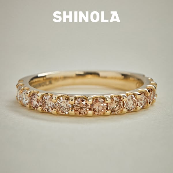 This ad showcases a close-up view of a gold ring with many small gems. The ring is in focus with the brand name at the t