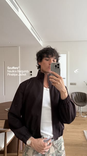 A man takes a selfie of himself wearing a jacket. The brand and product name are presented in the left side of the image