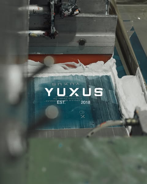 This ad uses an in-process printing press to showcase the clothing brand YUXUS.