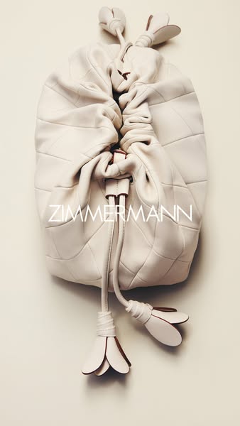 A product image of a Zimmermann bag against a cream background. The bag has a quilted pattern and a drawstring closure w