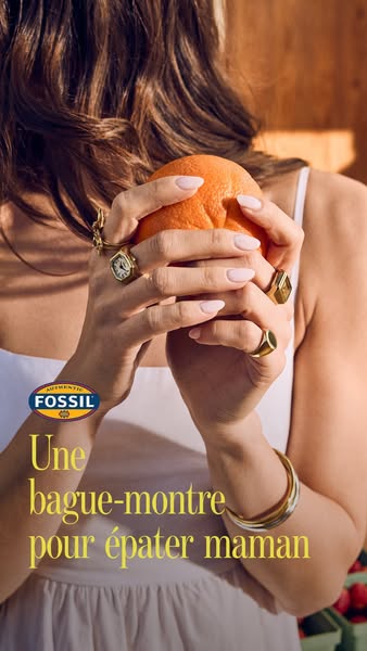 This ad from Fossil promotes a ring-watch for Mother's Day and features a model holding an orange while wearing seve