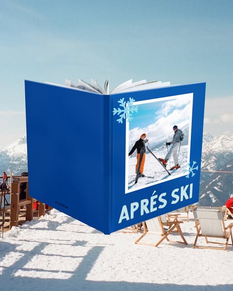 The image shows a book that is open, with a winter-themed picture on the book’s right page. The picture is of two skiers