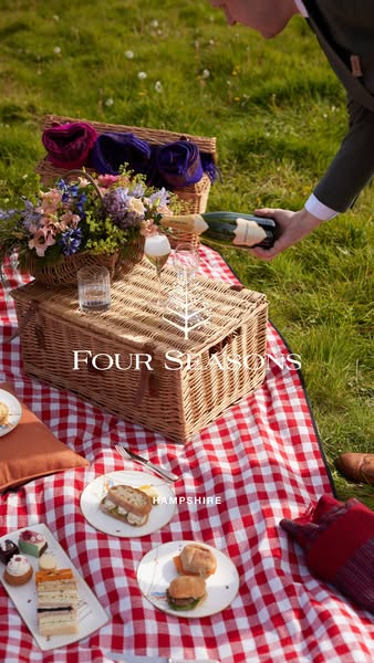 The ad features a picnic scene with a bottle of champagne being poured. The scene is designed to evoke a sense of luxury