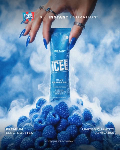 An image ad for ICEE Blue Raspberry electrolyte drink mix. It features a hand holding the product over a bed of blueberr