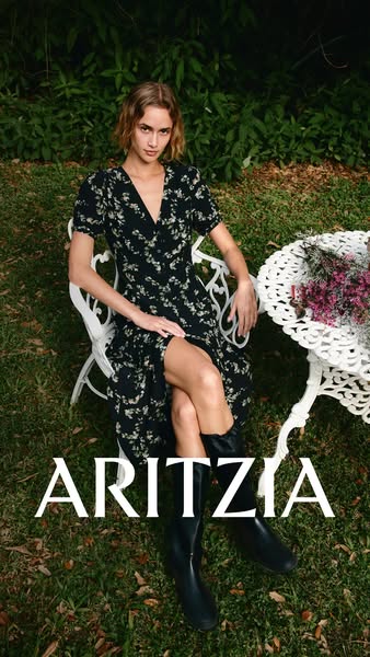This ad features a woman modeling a floral dress from Aritzia while sitting on a lawn.