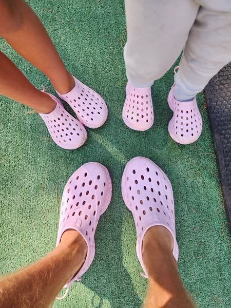 This image ad showcases a family wearing matching pink perforated shoes. The angle is slightly aerial, with the photogra