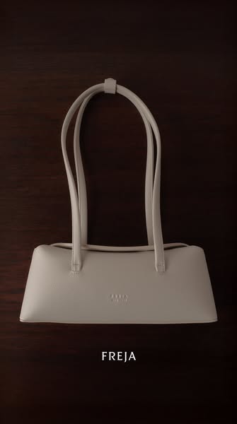 This ad features a static image of the FREJA handbag in a soft, neutral color, set against a dark background to highligh