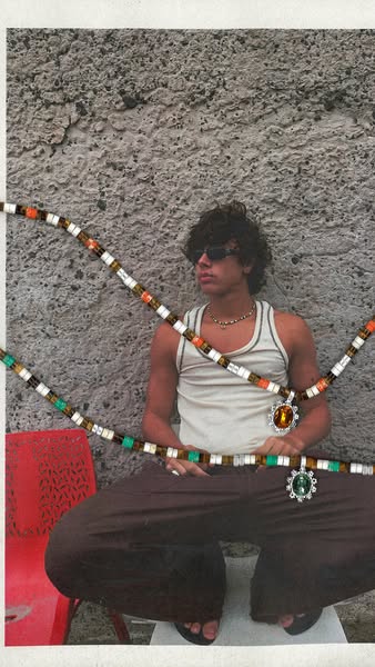 This image ad features a person sitting in front of a textured wall, showcasing two necklaces with large stone pendants.