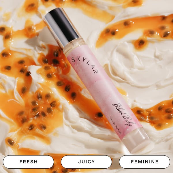 An image of the Skylar Blush Baby rollerball perfume, placed on top of what appears to be a bed of vanilla yogurt with p