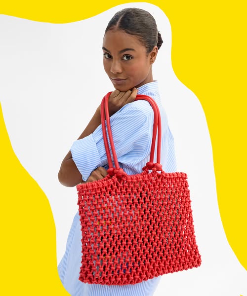 This image ad showcases a red woven tote bag worn over the shoulder by a person in a light blue striped button-down shir