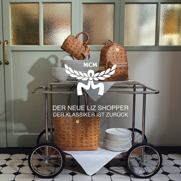 This ad showcases a range of MCM handbags on a serving cart, styled in a way that subverts typical luxury advertising wi
