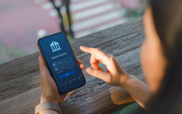 The ad shows a woman holding a smartphone and tapping the screen to log in to her mobile banking app. The image intends 