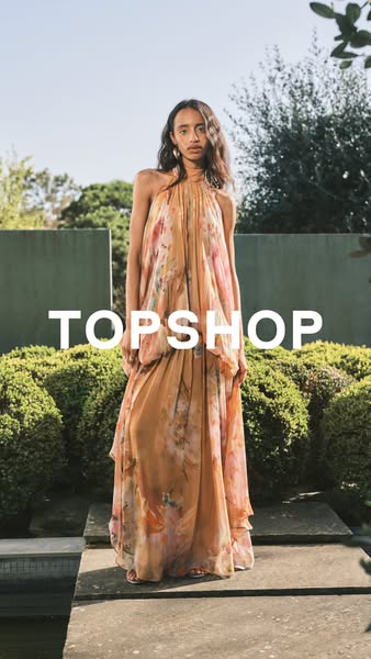 This ad features a model wearing a long, floral Topshop dress in an outdoor setting. The brand name is prominently displ