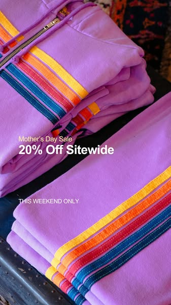 This image ad features a stacked display of lavender-colored clothing with rainbow-striped detailing to promote a "