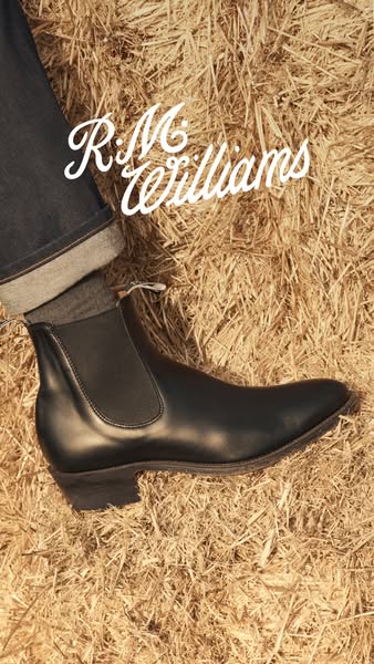 This image ad features a single black R.M. Williams boot placed on a bed of hay. It uses a close-up shot to highlight th