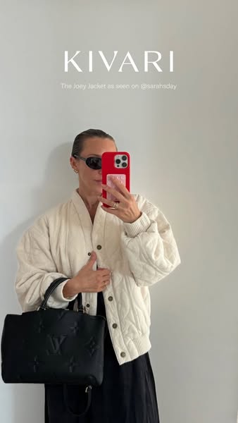 This image ad showcases a woman holding a smartphone while wearing a jacket from Kivari. The ad highlights the jacket as