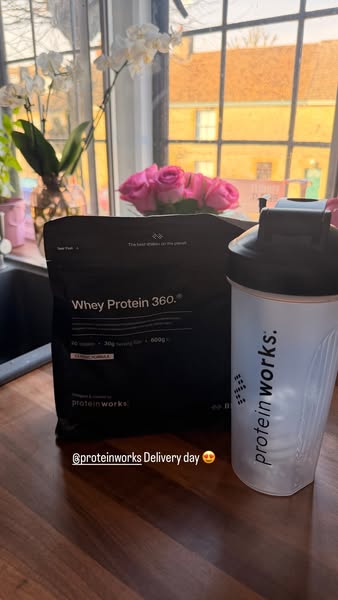 This image features Protein Works products. It is taken in a home kitchen with a protein powder product and shaker front