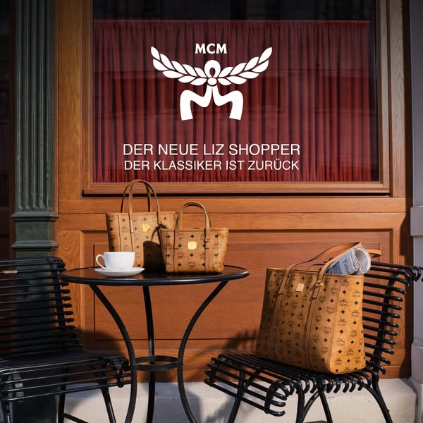 The ad showcases the MCM Liz Shopper handbag and features it sitting outside of a shop.