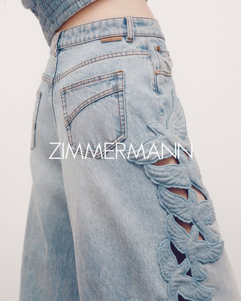 The ad features a close-up shot of the back of a pair of Zimmermann light-wash denim pants with a unique bird design on 