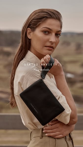 This ad features a woman holding a Status Anxiety clutch, showcasing the brand's new arrivals in a natural outdoor s