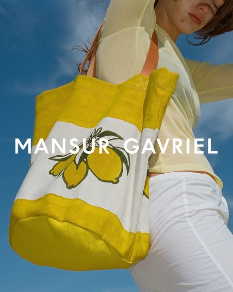 This ad features a woman wearing a yellow and white tote bag with a lemon print. The brand name, MANSUR GAVRIEL, is disp