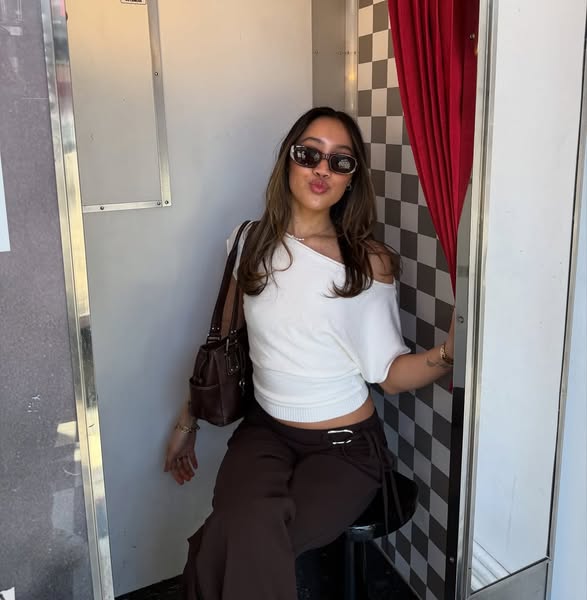 This ad features a woman in stylish clothing posing in a photo booth with a checkered background and a red curtain. The 