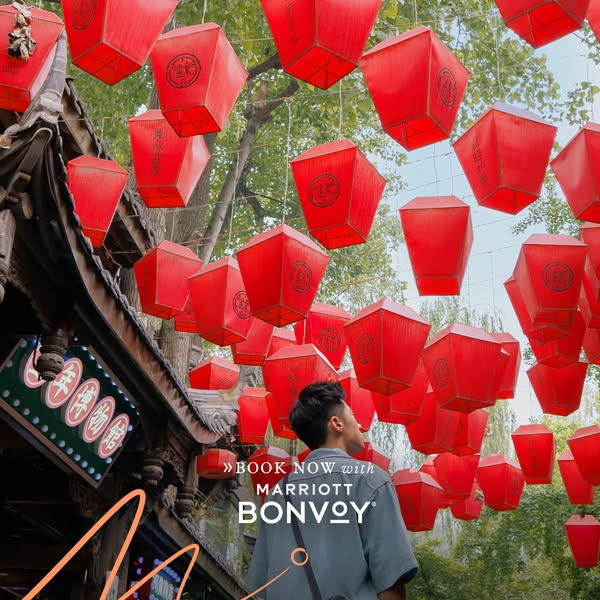 This ad for Marriott Bonvoy features a man looking up at a canopy of red lanterns in an outdoor setting.