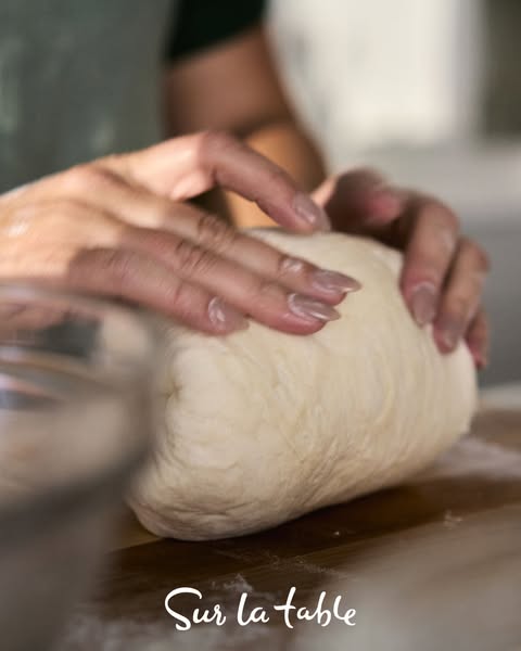 This ad shows a person kneading dough on a wooden surface, with the Sur la table logo visible at the bottom of the frame