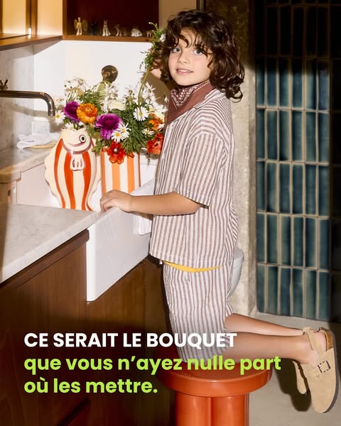 This ad features a young boy kneeling on a stool at a kitchen sink holding a large bouquet of flowers. The French text s
