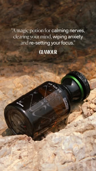 This image ad features a bottle of The Nue Co.'s Functional Fragrance, presented on a textured rock surface. A quote