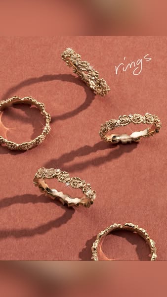This ad features five gold rings with floral accents arranged on a brown surface. The word 'rings' is written in