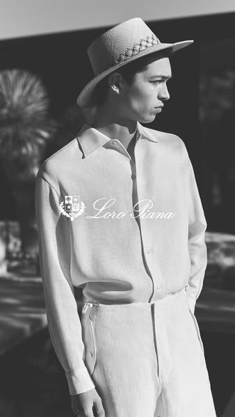 A black and white image ad featuring a male model wearing Loro Piana apparel including a straw hat, shirt, and pants.