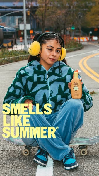This ad features a young woman sitting on a skateboard in an urban environment, holding a bottle of Sun Bum sunscreen. T